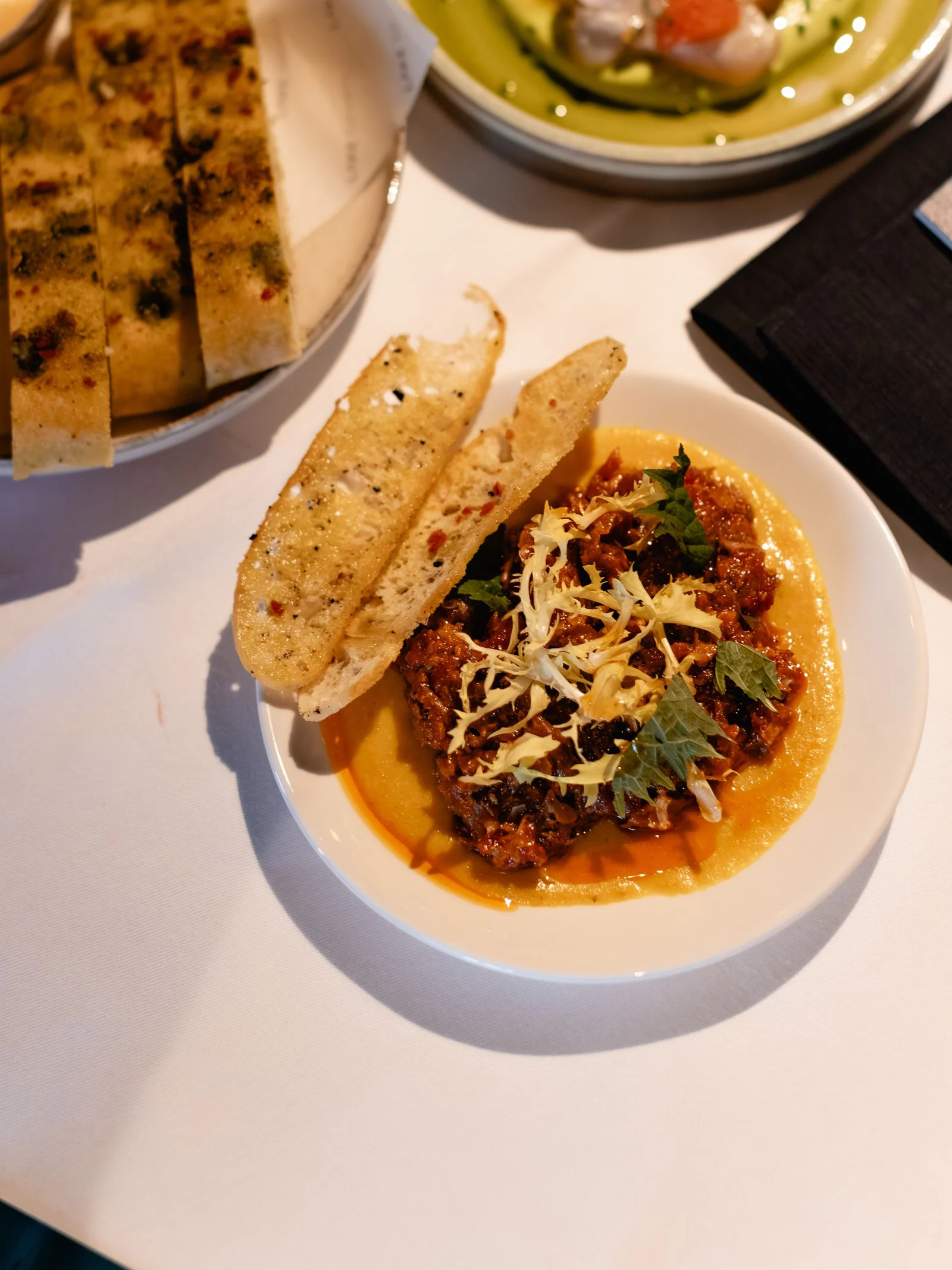 Ragù met focaccia en gegrilde crostini op tafel, met ceviche ernaast